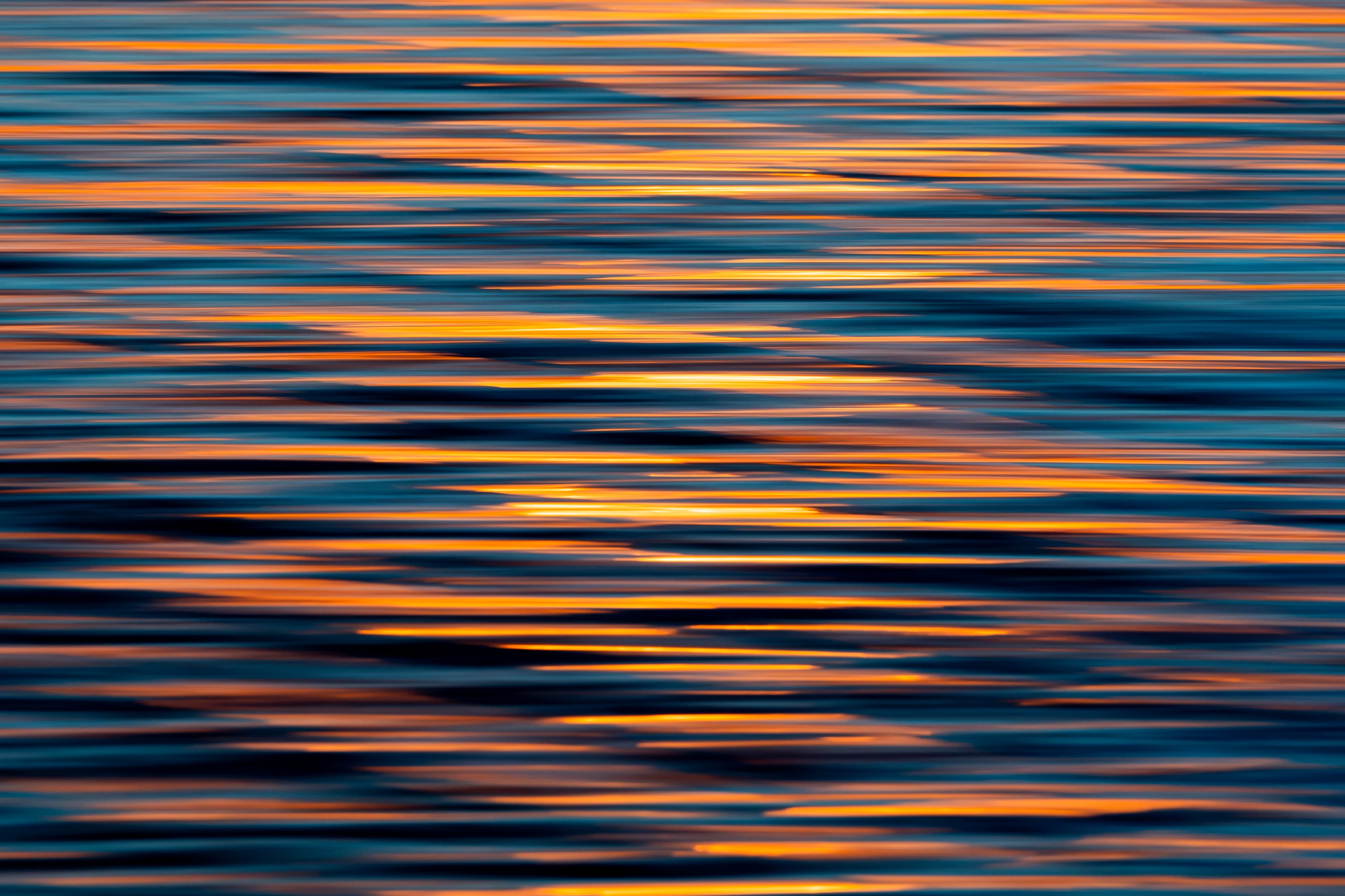 Copper sunset light streaked across still water — fine art ocean photography print, Whangamata NZ.