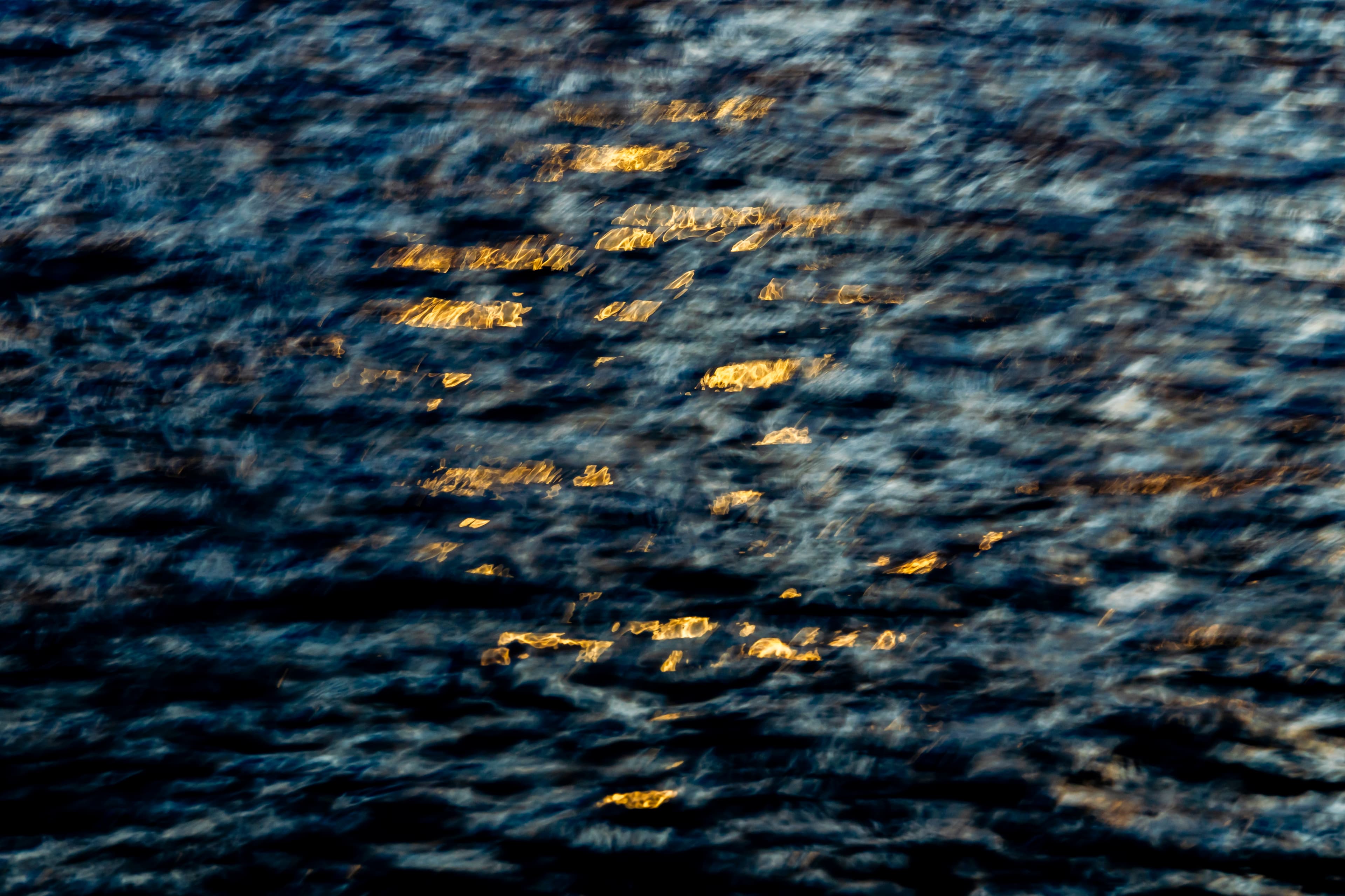 Dark water flecked with warm golden light — fine art ocean photography print, Whangamata NZ.