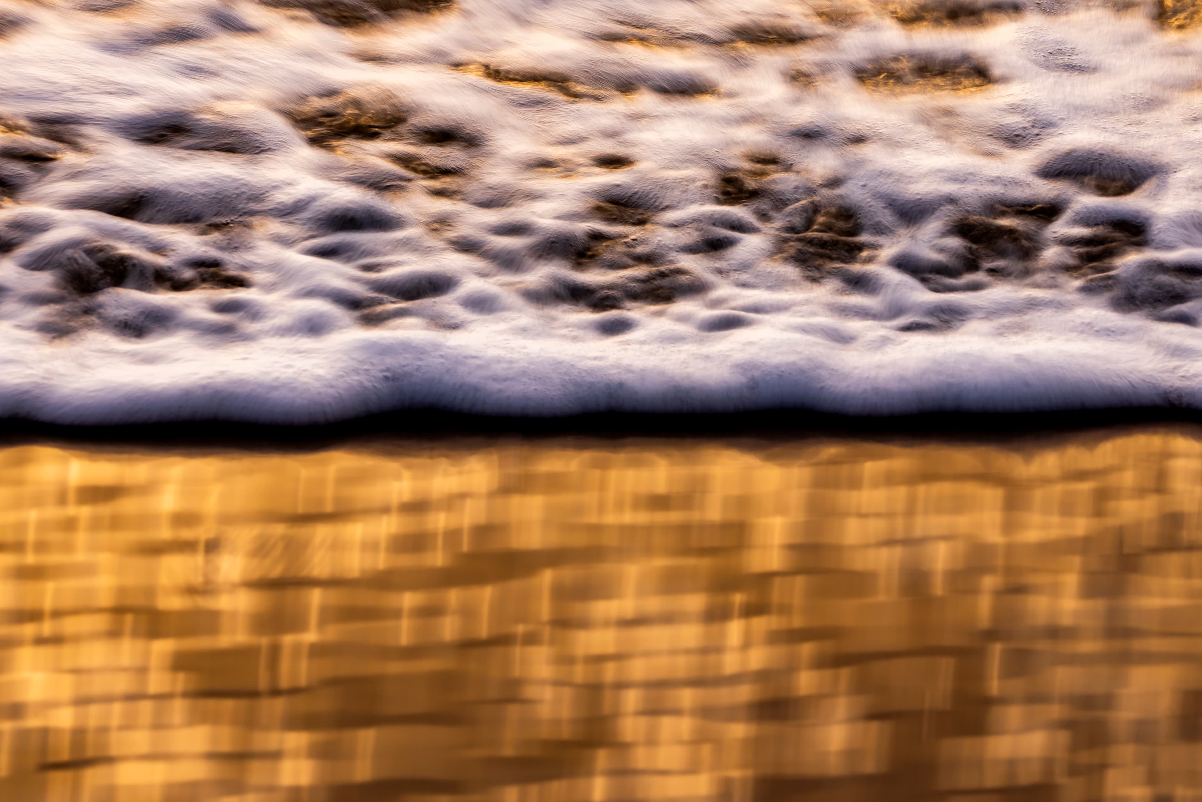 Golden sea foam breaking over amber sand — fine art ocean photography print, Whangamata NZ.