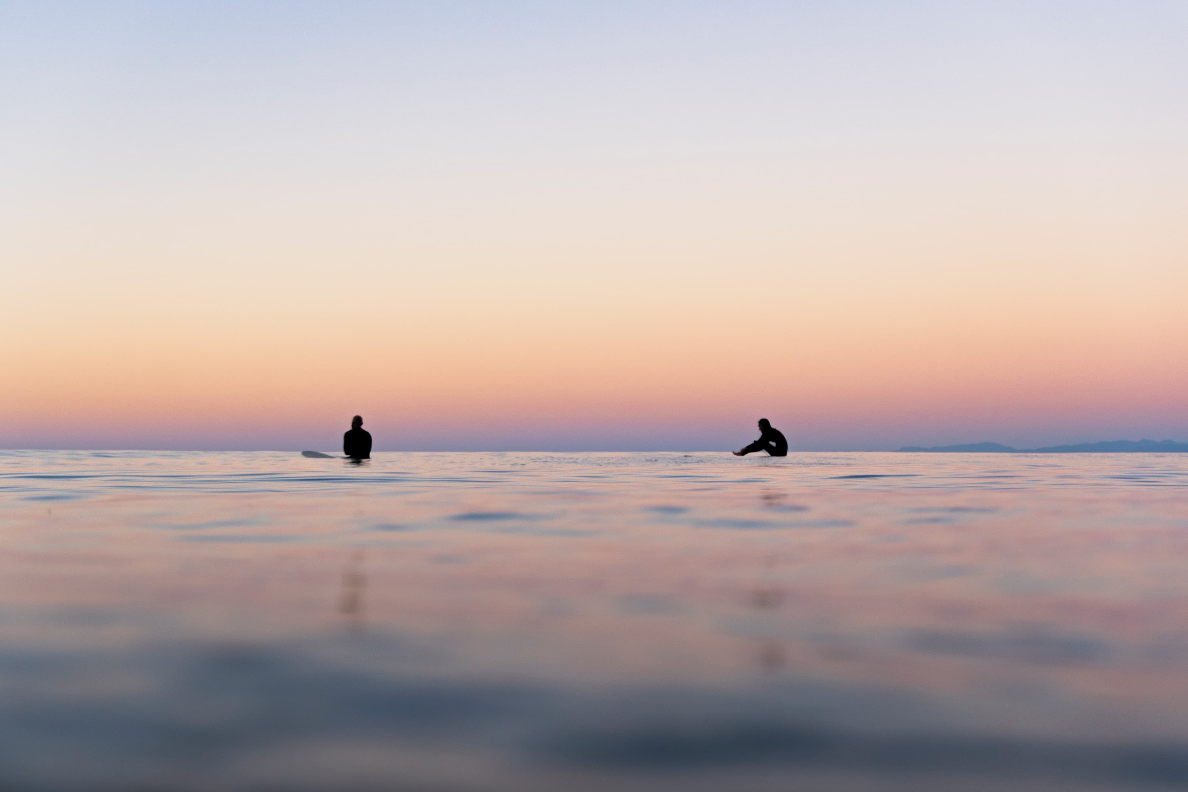 Two figures silhouetted on still water at dusk — fine art ocean photography print, Whangamata NZ.